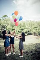 Groupe de copines heureux tenant des ballons multicolores dans un parc photo