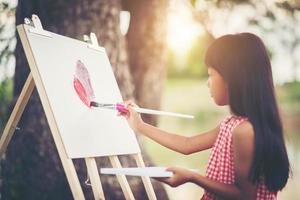 petite fille artiste peignant une image dans le parc photo
