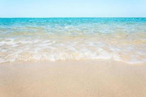 vagues de l'océan sur la plage de sable avec un ciel bleu clair photo
