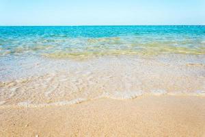 vagues de l'océan sur la plage de sable avec un ciel bleu clair photo