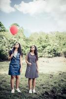 Groupe de copines heureux tenant des ballons multicolores dans un parc photo