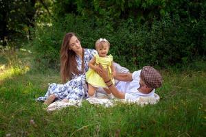 une jeune famille heureuse joue avec leur petite fille au pré vert photo