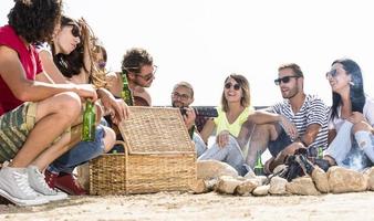 été, vacances, vacances, musique, concept de gens heureux - groupe d'amis avec guitare s'amusant sur la plage photo