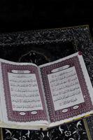 al-quran qui est au-dessus du tapis de prière avec un fond noir photo