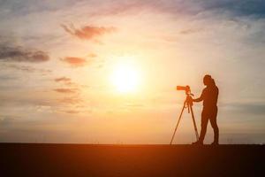 silhouette d'un photographe tirant au coucher du soleil photo