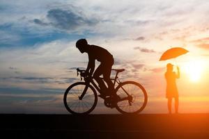 jeune homme fait du vélo sur fond de coucher de soleil photo