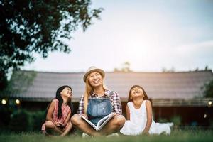 mère racontant une histoire à ses deux petites filles dans le jardin potager photo