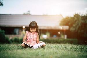 Petite fille lisant un livre dans son jardin à l'extérieur photo