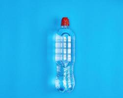 bouteille en plastique transparente avec de l'eau fraîche sur fond bleu photo