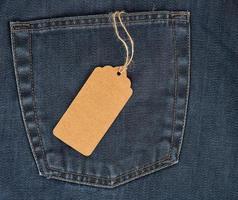 attaché sur une corde est une étiquette de papier brun rectangulaire vide sur un jean bleu photo