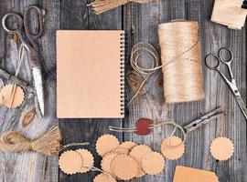 bloc-notes ouvert avec des feuilles vides brunes sur une table en bois grise, à côté se trouvent une corde photo