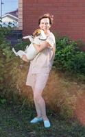 jeune femme portant des vêtements de maison tenant un chien jack russell terrier près de sa maison dans la cour arrière - propriétaire d'animal et animal photo