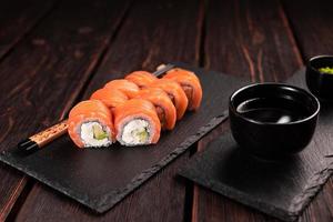 sushi roll philadelphia avec saumon et concombre et fromage à la crème sur fond noir. menu de sushis. concept de cuisine japonaise photo