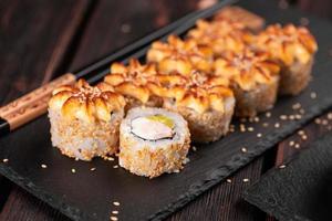 sushi roll philadelphia avec crabe avocat et fromage à la crème sur fond noir gros plan. menu de sushis. concept de cuisine japonaise photo