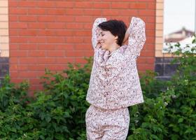 Cheerful woman in home wear pyjama outdoor brick wall backyard background émotions copie espace - vêtements de nuit et homewear concept photo