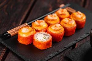 rouleau de sushi californien avec concombre de crabe et caviar de tobiko servi sur un tableau noir en gros plan - cuisine asiatique japonaise photo