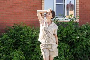 Cheerful woman in home wear pyjama outdoor brick wall backyard background émotions copie espace - vêtements de nuit et homewear concept photo