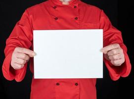 chef en uniforme rouge tenant une feuille de papier blanc vierge photo