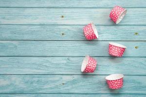 étuis à cupcakes roses à pois sur un plancher en bois bleu. matériel de cuisson. photo