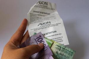 jakarta, indonésie en décembre 2022. photo blanche isolée d'une main tenant un reçu d'achat après avoir fait du shopping au centre commercial aeon