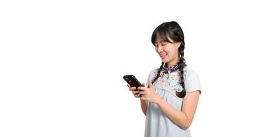 portrait d'heureuse belle jeune femme asiatique en robe denim à l'aide d'un smartphone sur fond blanc. tourné en studio photo