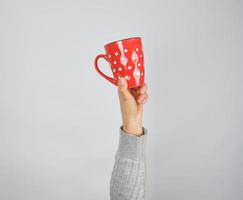 tasse en céramique rouge dans une main féminine sur fond blanc photo