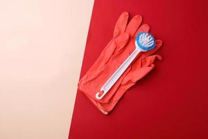 brosse blanche et gants en caoutchouc rose pour nettoyer la maison sur fond rouge-beige photo