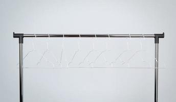 des cintres en métal blanc vides s'accrochent à une barre chromée, fond blanc photo