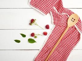 cuillère en bois et serviette rouge textile sur une table en bois blanche photo