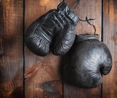 très vieux gants de boxe noirs sur fond de bois marron photo