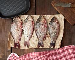 le poisson crucian frais saupoudré d'épices se trouve sur du papier froissé marron photo