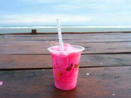 es podeng ou boisson rose sur une table en bois avec fond de plage, indonésie photo