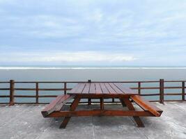 un banc de plage en bois au-dessus du pont côtier d'une île tropicale. vacances de détente avec mer turquoise et paysage de ciel bleu. le concept de voyage de vacances d'été photo