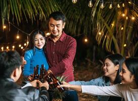 portrait d'amis asiatiques heureux en train de dîner ensemble - jeunes gens grillant des verres à bière dîner en plein air - gens, nourriture, style de vie des boissons, concept de célébration du nouvel an. photo