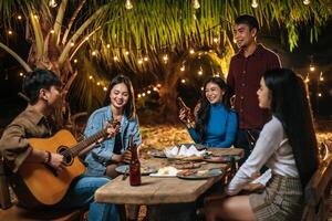 portrait d'un groupe d'amis asiatiques heureux s'amusant à manger de la musique et à boire ensemble en plein air - groupe d'amis heureux grillant des bières - gens, nourriture, style de vie des boissons, concept de célébration du nouvel an. photo