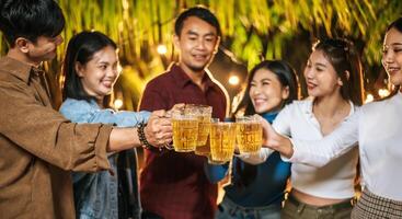 portrait d'amis asiatiques heureux en train de dîner ensemble - jeunes gens grillant des verres à bière dîner en plein air - gens, nourriture, style de vie des boissons, concept de célébration du nouvel an. photo