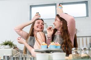 mère et fille enjouées rient et sourient en montrant un gâteau photo