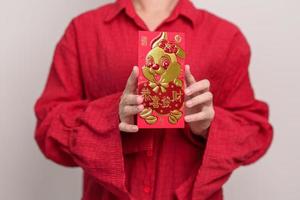 femme tenant une enveloppe rouge chinoise avec lapin doré et mot de bénédiction, cadeau en argent pour les vacances du nouvel an lunaire. phrase chinoise signifie bonheur, en bonne santé, chanceux et riche photo