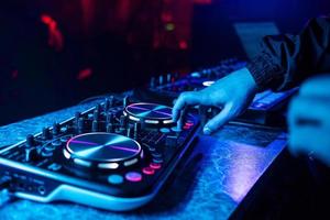 console dj pour mixer de la musique avec les mains et avec des personnes floues dansant lors d'une soirée en boîte de nuit photo