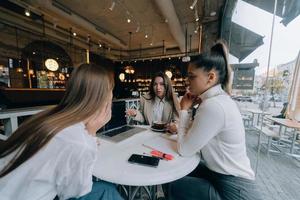 un groupe d'amies dans un café travaillant sur un projet photo