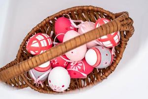 panier en osier avec oeufs de pâques colorés, sur fond blanc à l'époque de pâques 2023 photo