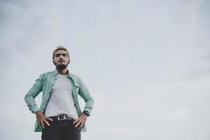 jeune homme hipster debout dans un parc avec ciel photo