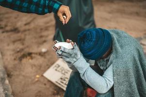 mendiant enveloppé de tissu dans la rue acceptant de l'argent photo