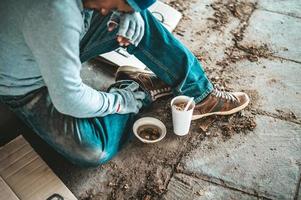 mendier sous le pont avec une tasse contenant des pièces et des nouilles instantanées photo