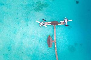 belle vue aérienne de la jetée des maldives vue de dessus d'hydravion avec bateau en bois et plage tropicale. complexe tropical de luxe ou hôtel avec des villas sur l'eau et de beaux paysages de plage. vue imprenable sur les yeux d'oiseau photo