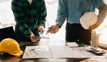 architecte créatif projetant sur les grands dessins dans le bureau loft sombre ou le café à la lumière du soleil photo