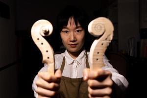 jeune femme chinoise luthier montrant le manche des violons en construction photo