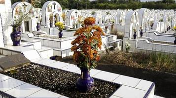 pierre tombale et fleurs dans un vase sur une tombe en céramique blanche dans un cimetière ou un cimetière. photo