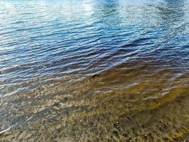 surface de l'eau avec des vagues et des ondulations et la lumière du soleil se reflétant à la surface. photo