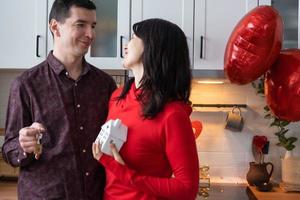 homme et femme amoureux datent à la maison dans la cuisine avec les clés de la maison. saint valentin, couple heureux, histoire d'amour. nid d'amour, hypothèque, déménagement, achat, immobilier, logement pour jeune famille photo